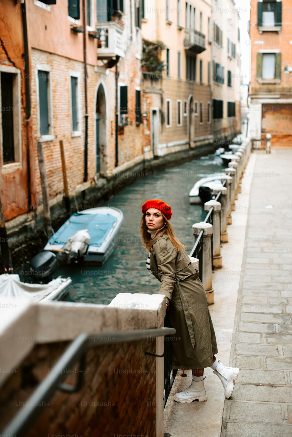a woman leaning on a railing next to a canal