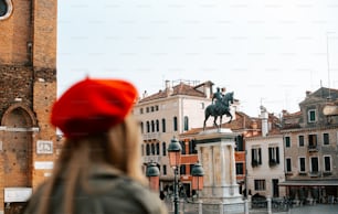 a woman wearing a red hat looking at a statue