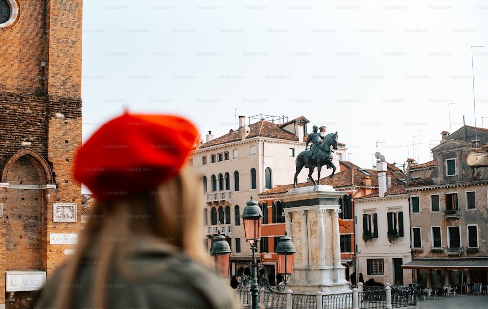 uma mulher que usa um chapéu vermelho olhando para uma estátua