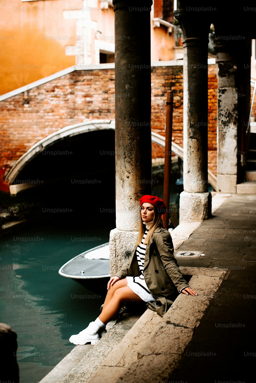 a woman sitting on a ledge next to a canal