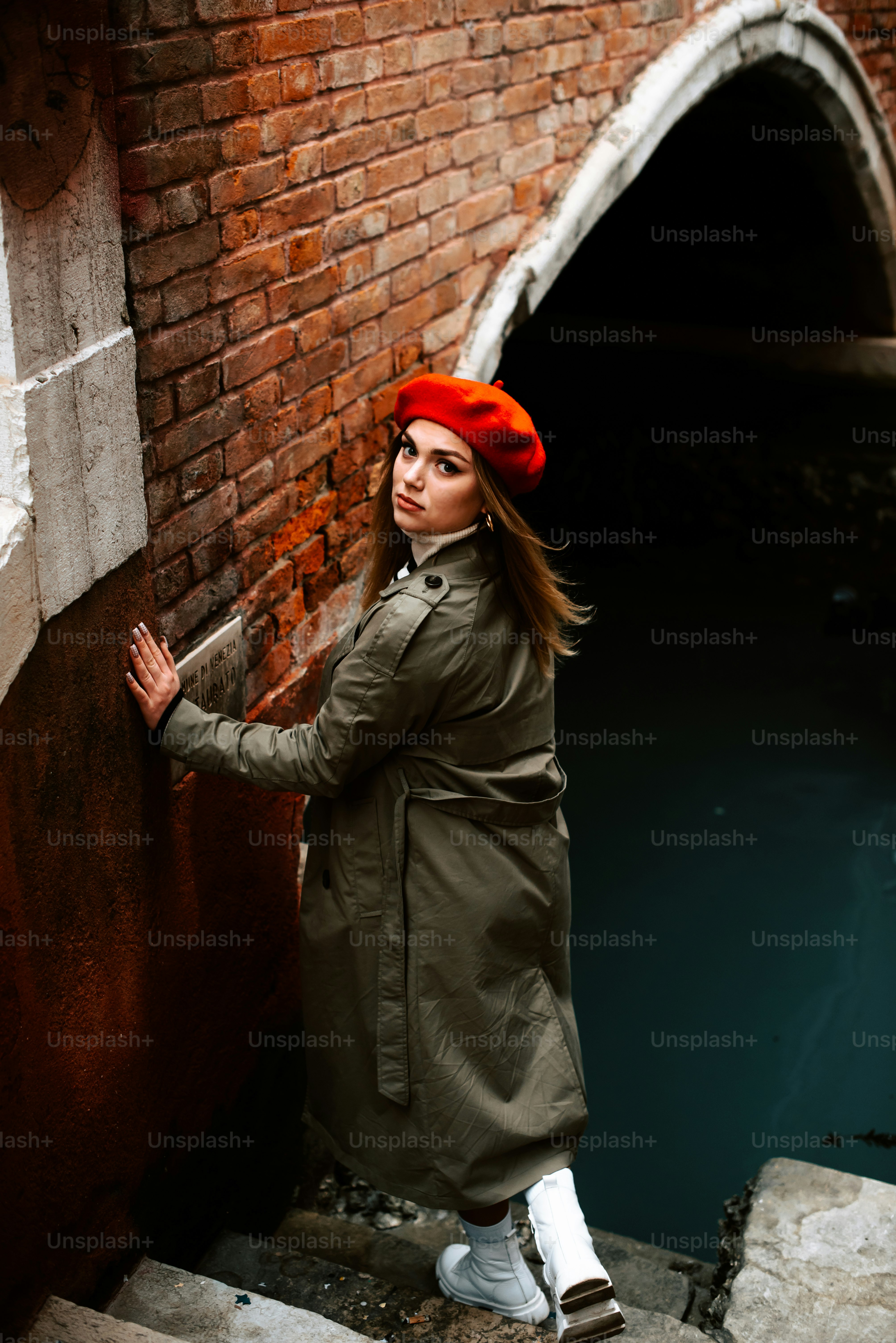 A woman in a red hat leaning against a brick wall photo – Style Image ...