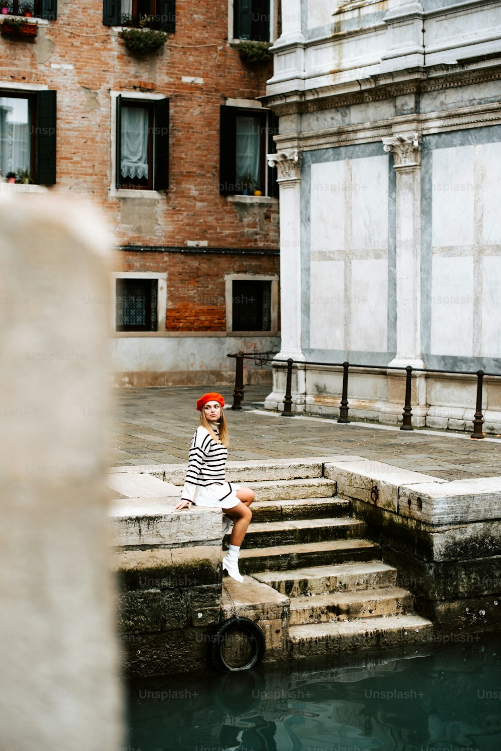 una donna seduta sui gradini accanto a uno specchio d'acqua