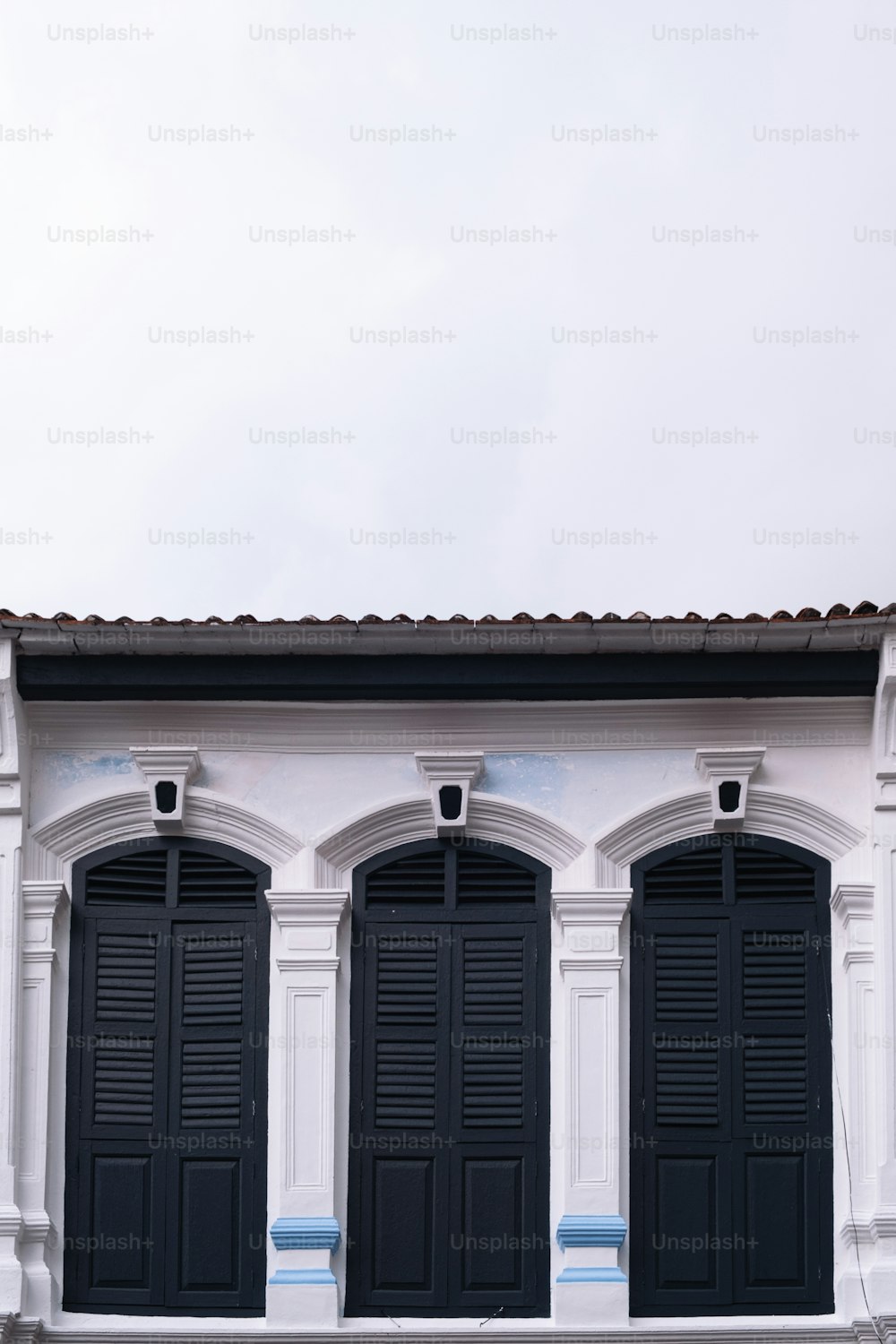 a white building with black shutters and a clock