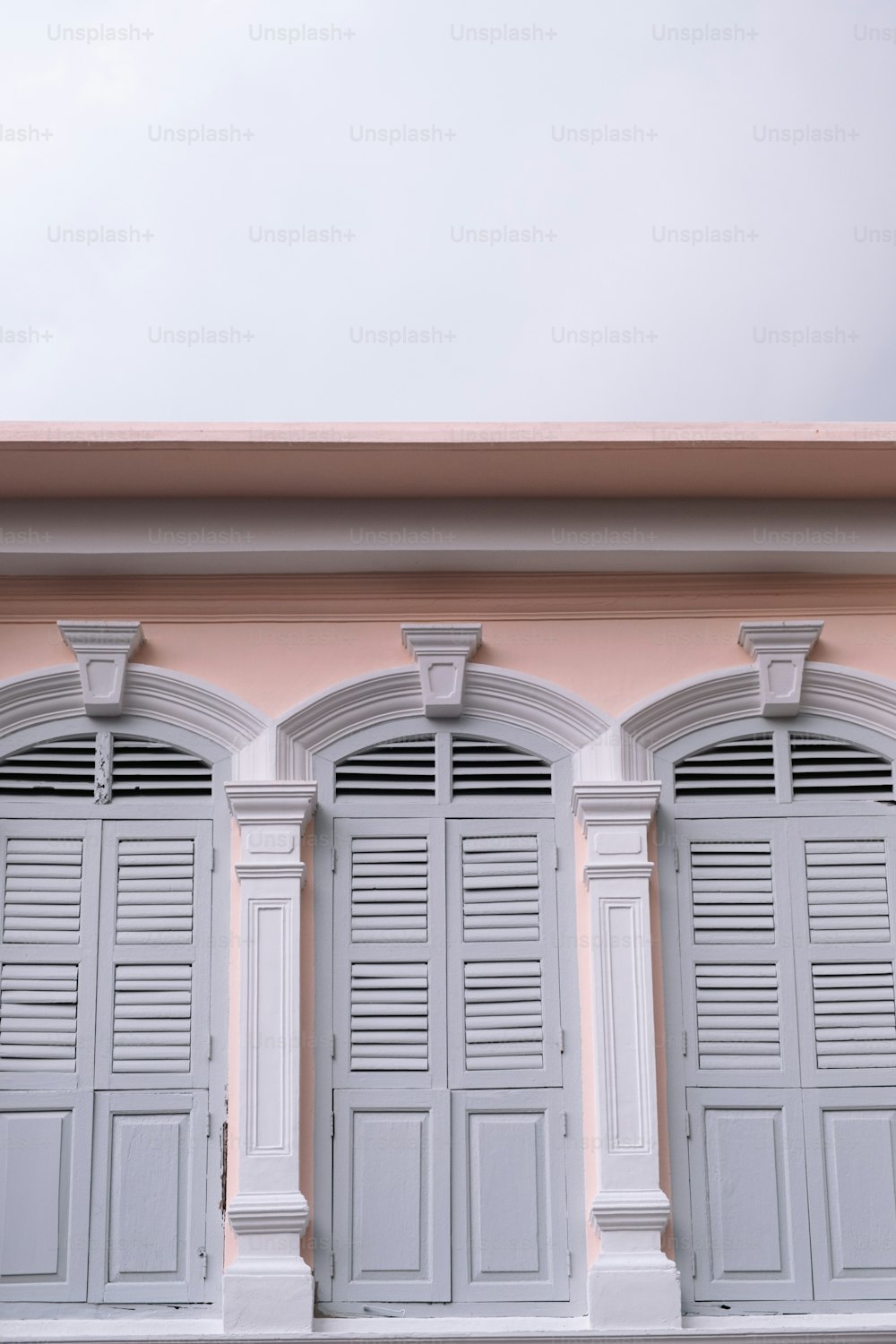 a row of white shutters on a pink building