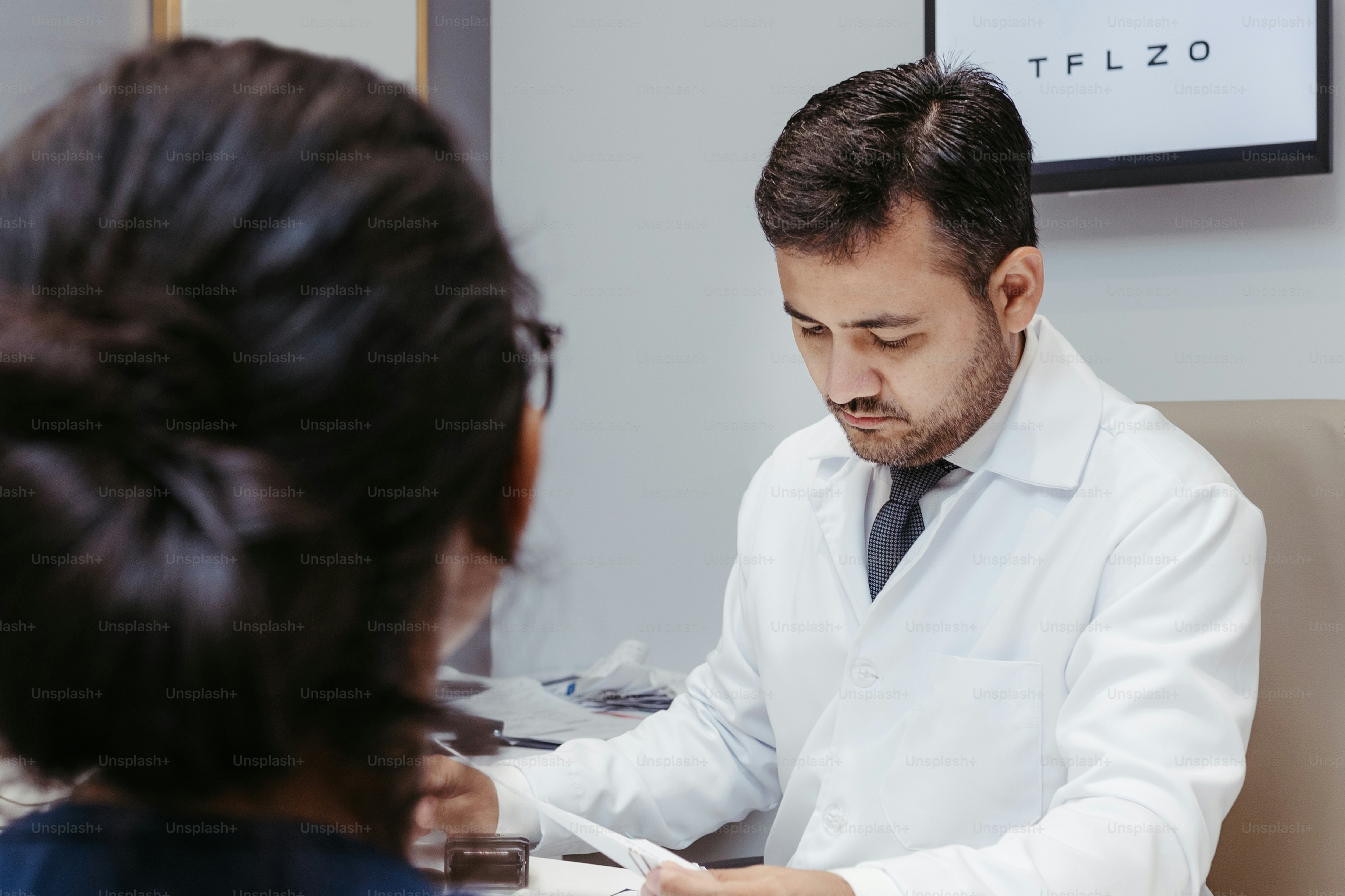 A man sitting at a desk in front of a woman photo – Doctor Image on Unsplash, image size:3000x2000