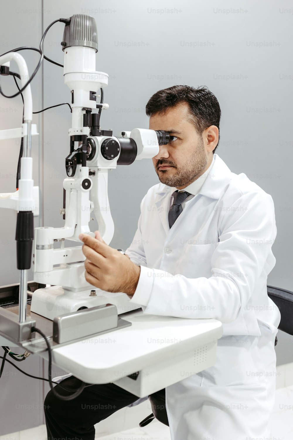 현미경을 통해 보고 있는 흰색 실험실 코트를 입은 남자