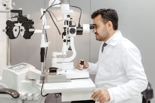 a man in a white lab coat looking through a microscope