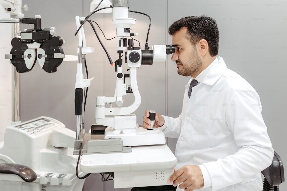 Ein Mann im weißen Laborkittel schaut durch ein Mikroskop