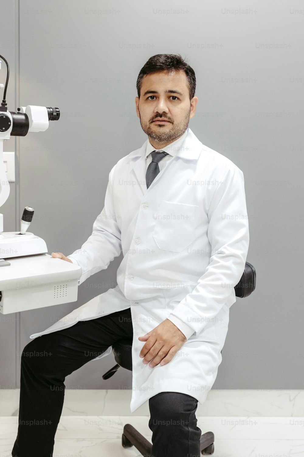 a man in a white lab coat sitting in front of a microscope