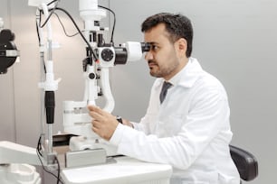 a man in a white shirt and tie looking through a microscope