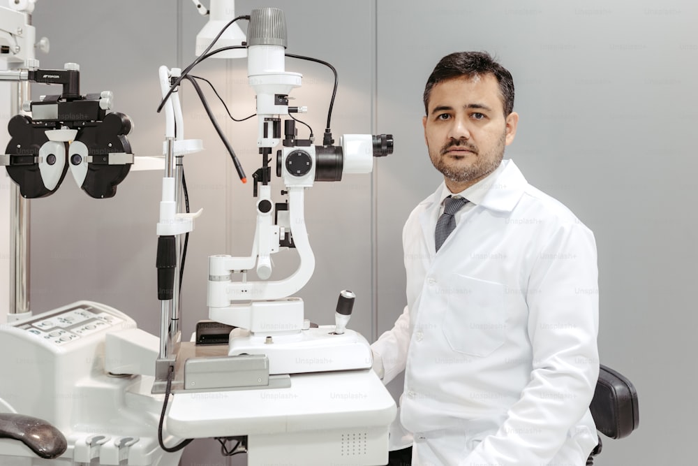 Un uomo in camicia bianca e cravatta in piedi davanti a un microscopio