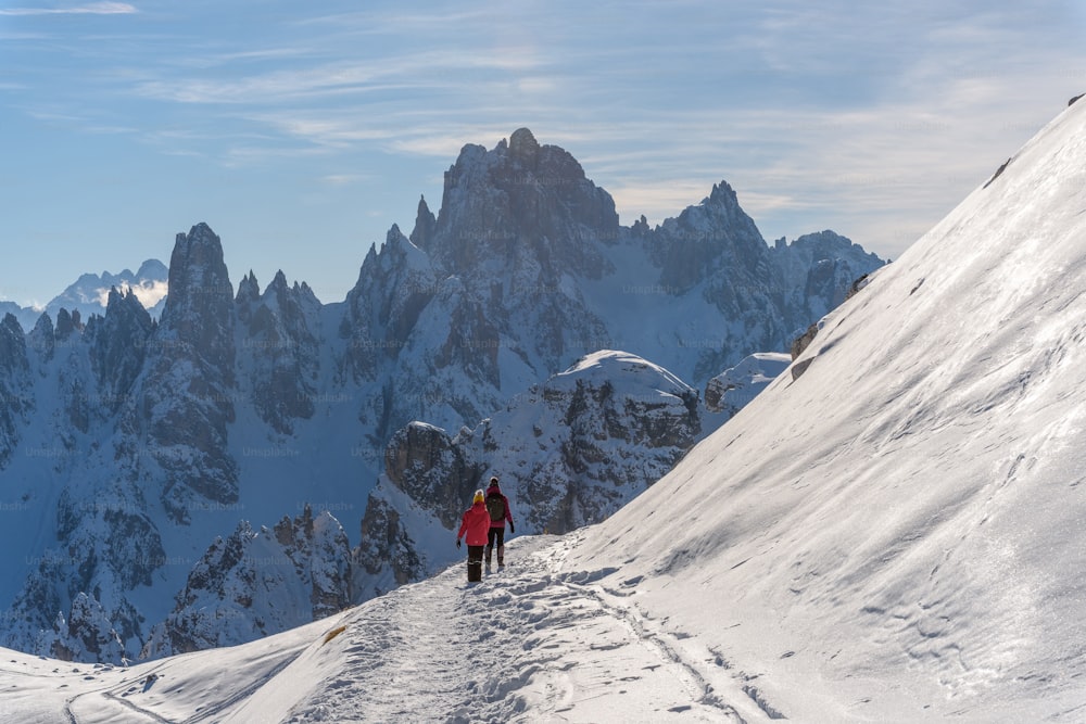 two people walking up a snow covered mountain