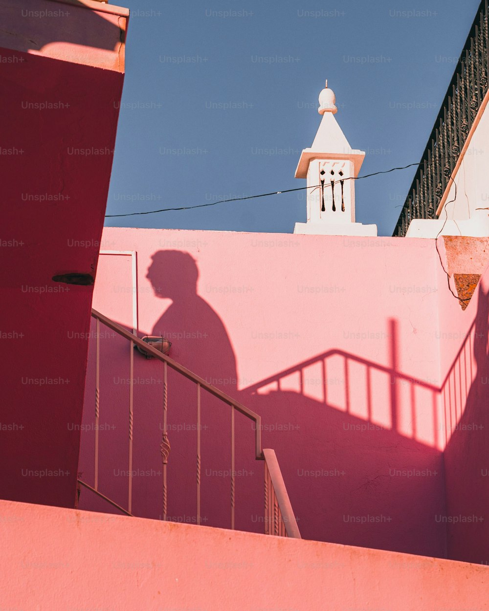 uma sombra de um homem em uma parede rosa