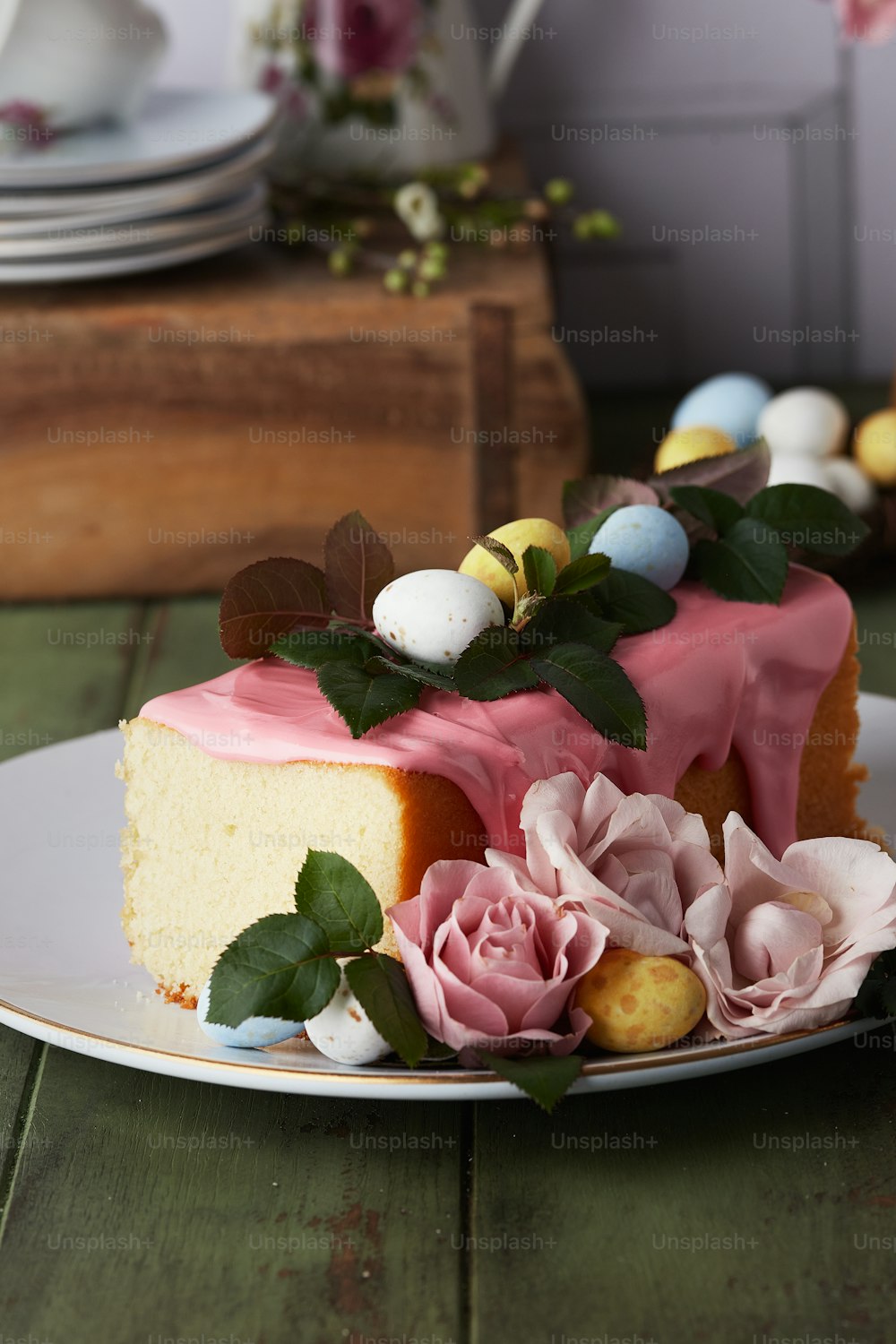 Ein Stück Kuchen mit rosa Glasur und Blumen auf einem Teller