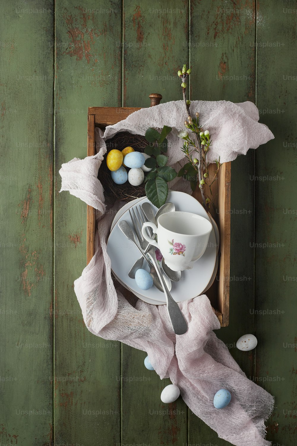 a tray with a teacup, plate, spoon, and flowers on it