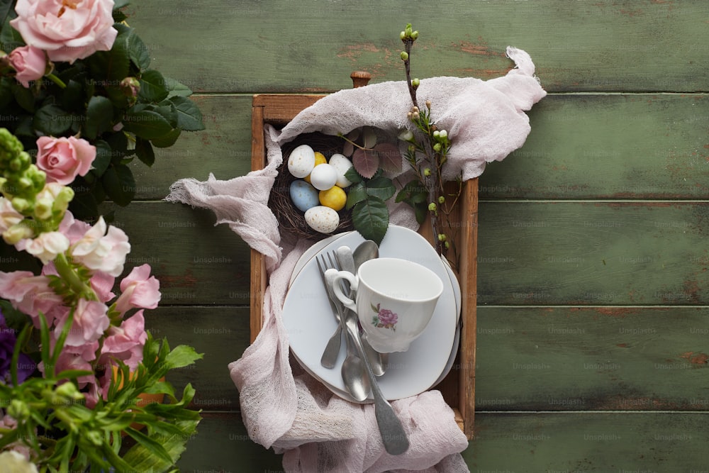 a plate with a cup and saucer on it next to flowers