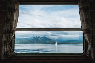 uma janela com vista para um lago e montanhas