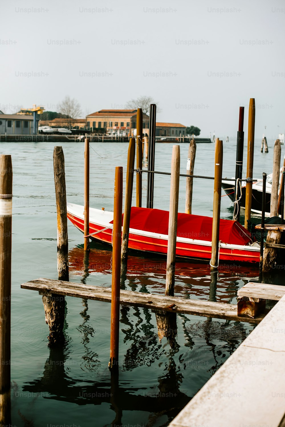 a red boat is docked at a pier