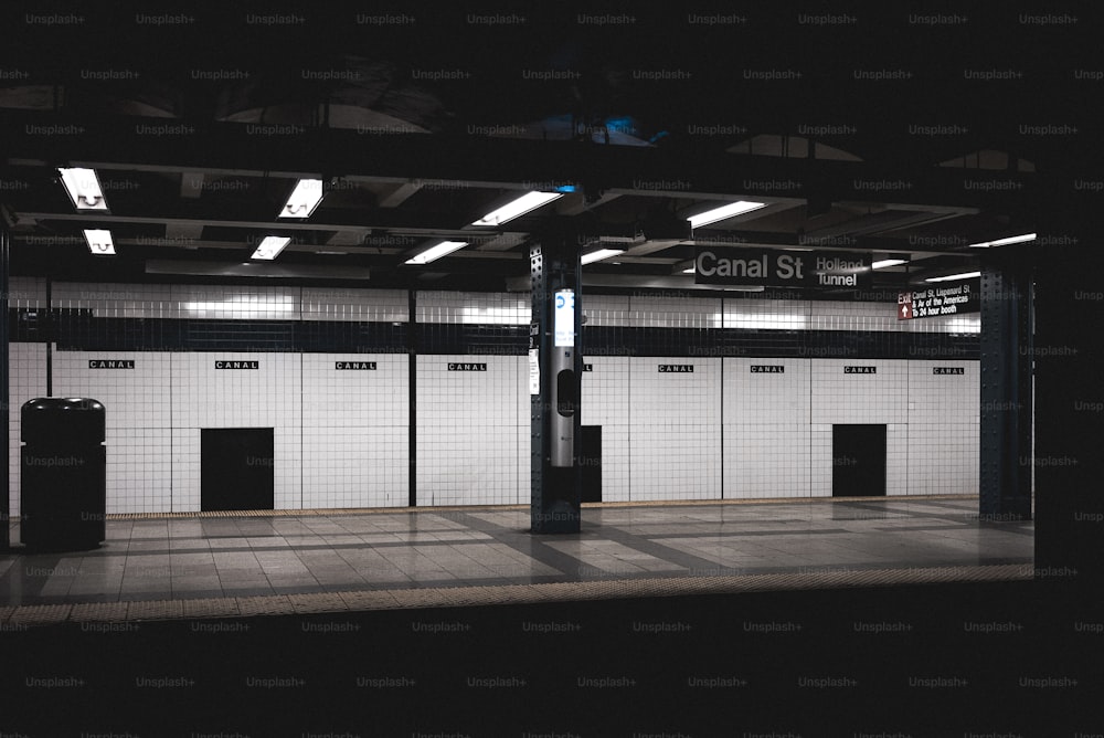 une station de métro avec un sol carrelé noir et blanc
