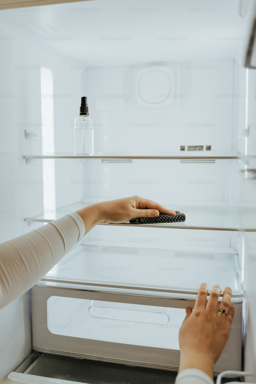 a woman holding a remote control in front of a refrigerator