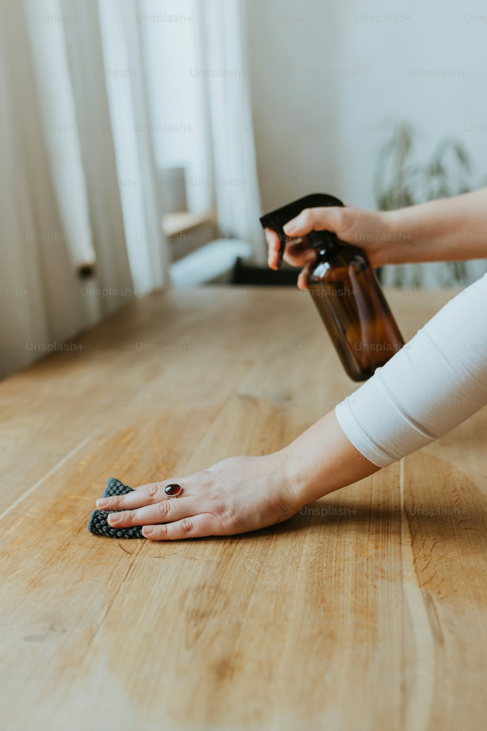Une femme nettoie un plancher en bois avec une bouteille