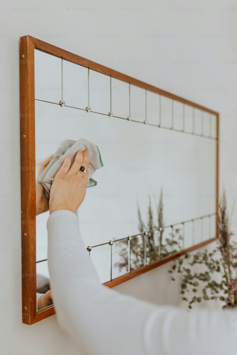 una donna che pulisce uno specchio con un panno
