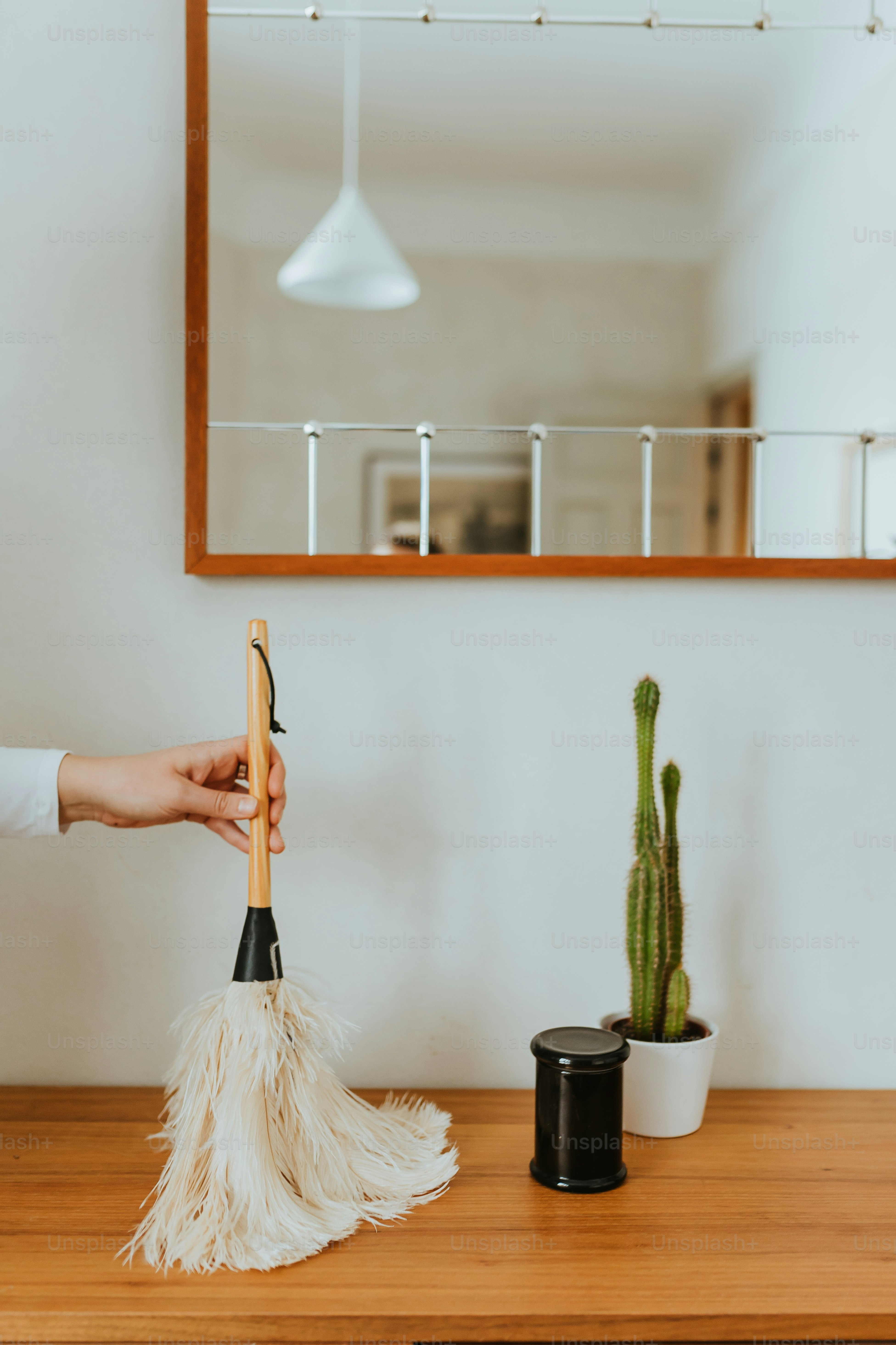 una persona che pulisce un tavolo con una scopa per la polvere