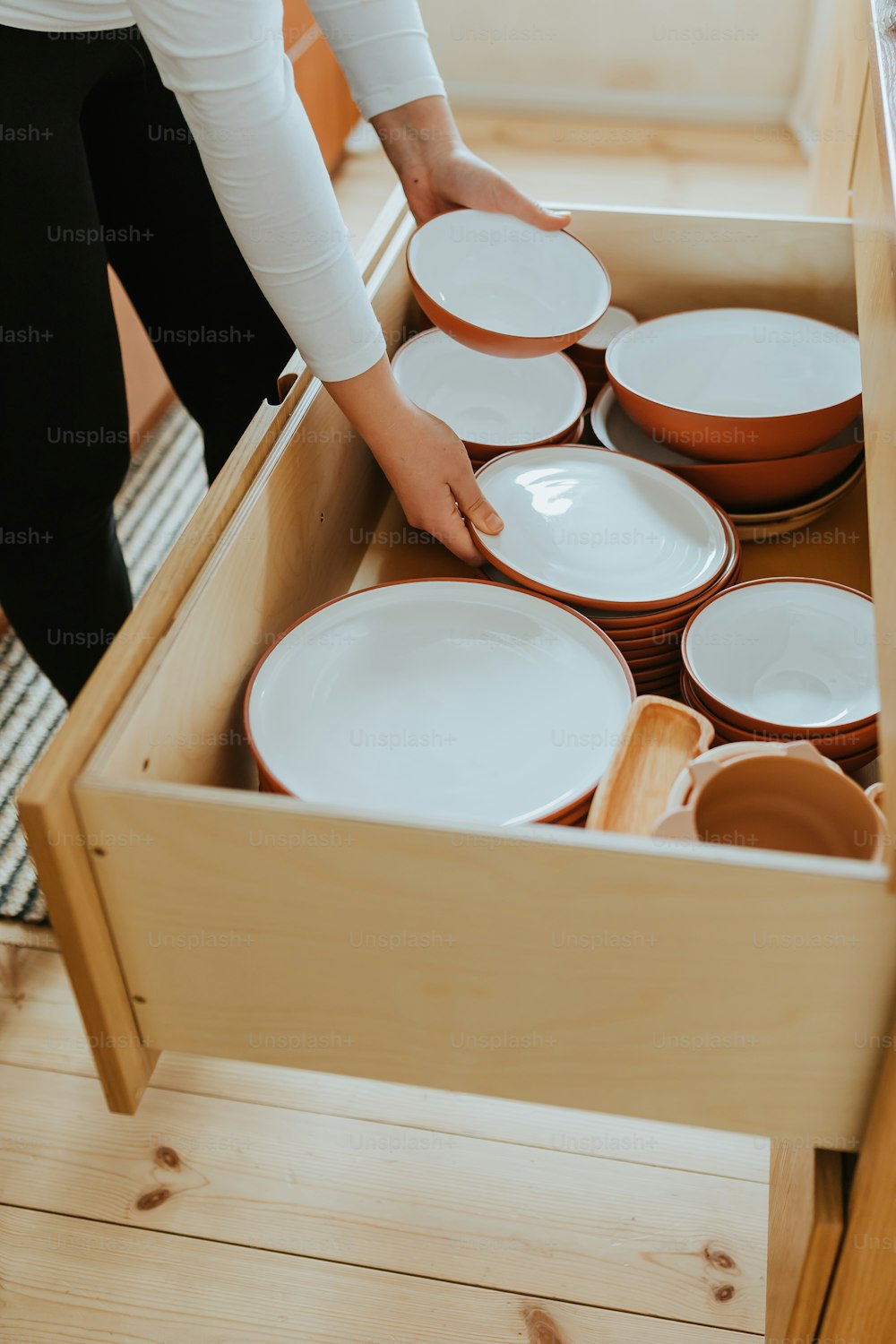 uma pessoa colocando pratos em uma gaveta