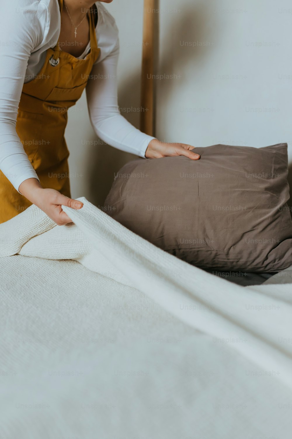 Una mujer poniendo una almohada encima de una cama