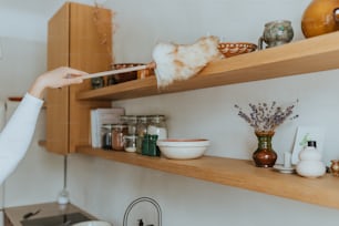 a woman cleaning a shelf in a kitchen