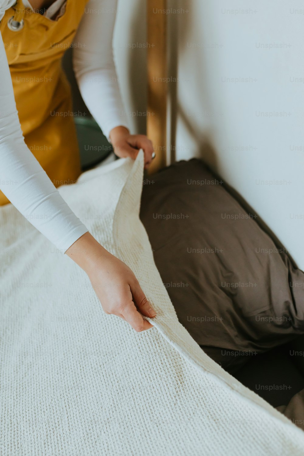 Una donna sta facendo un letto con una coperta bianca