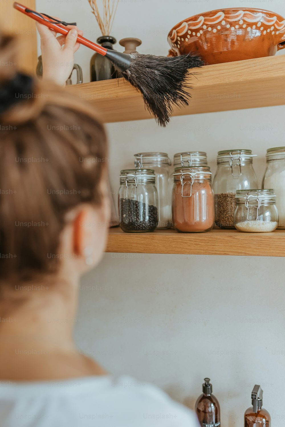 a woman standing in front of a shelf filled with jars