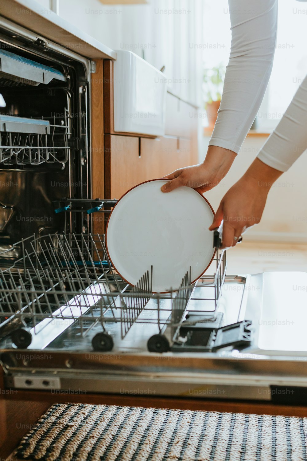 uma mulher está colocando um prato na máquina de lavar louça
