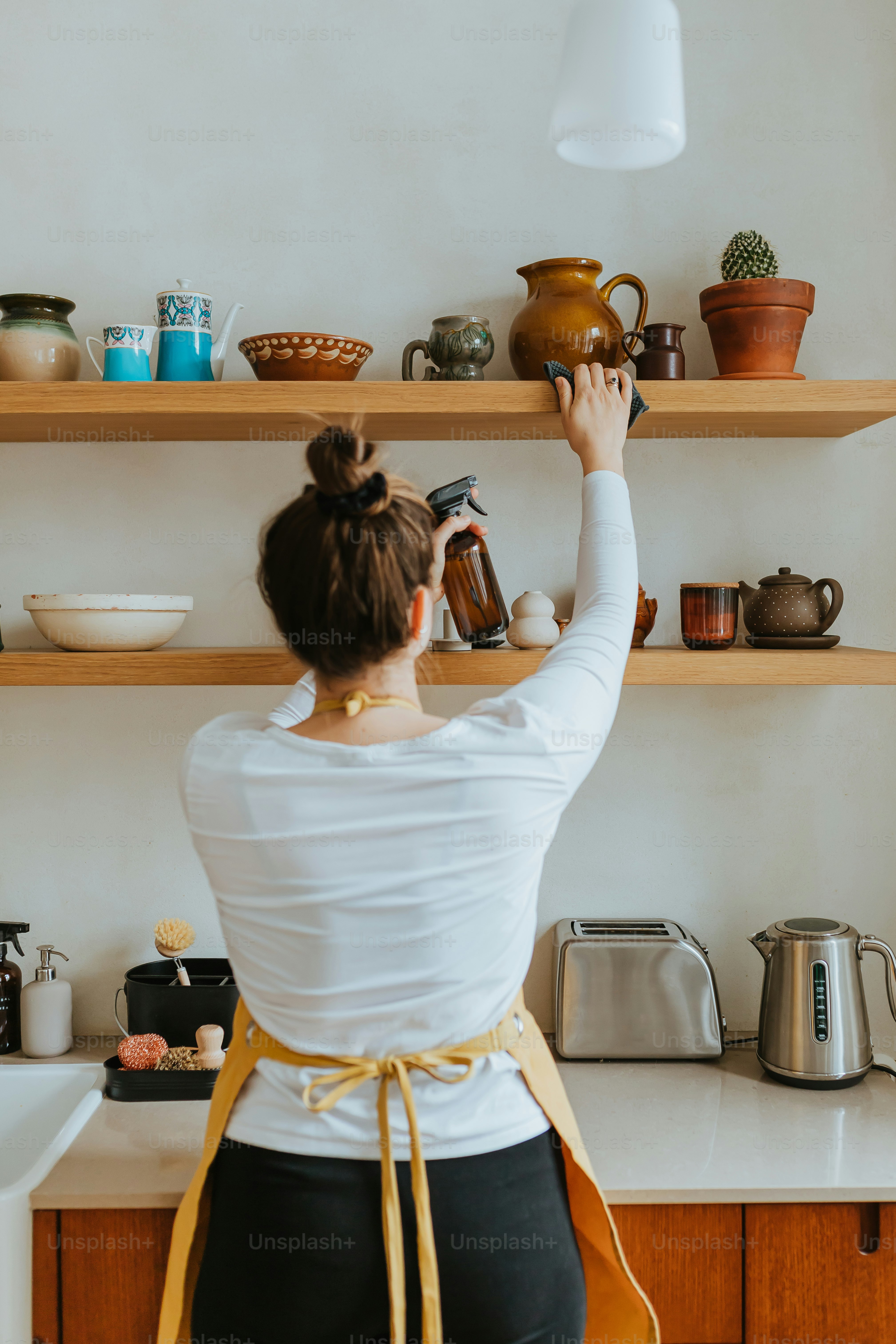 棚の前に立ち、ボトルを持つ女性