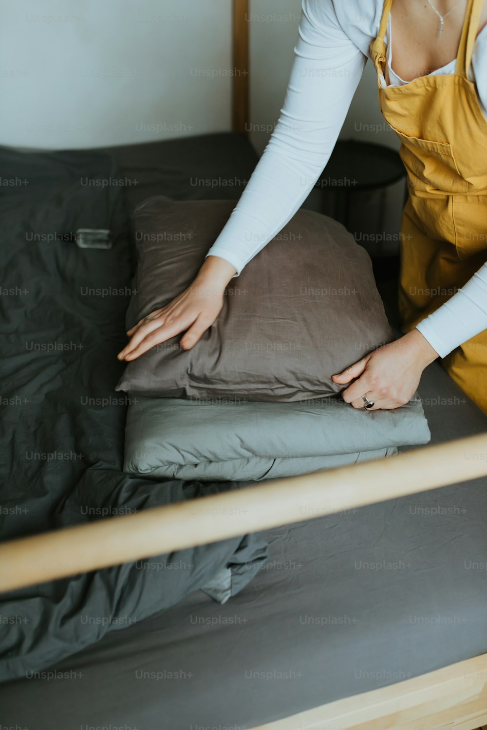 uma mulher em um vestido amarelo está colocando um travesseiro em uma cama