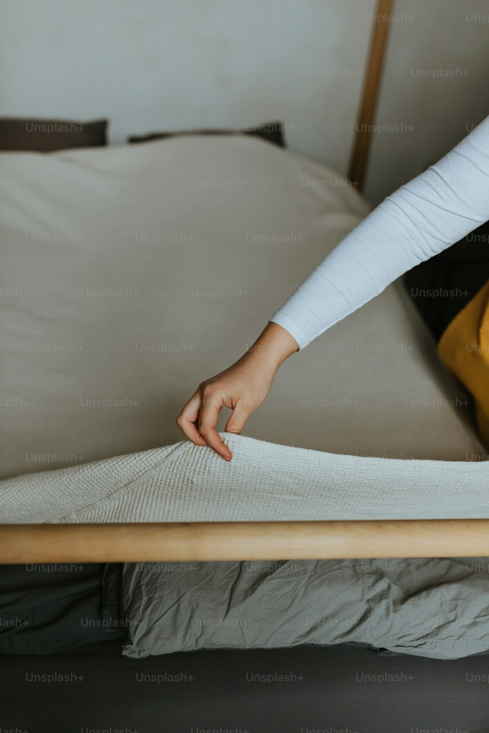 a woman putting a mattress on top of a bed