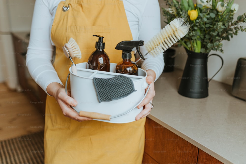 a woman holding a bucket of cleaning products