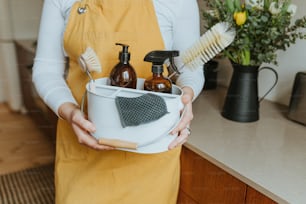 a woman holding a bucket of cleaning products