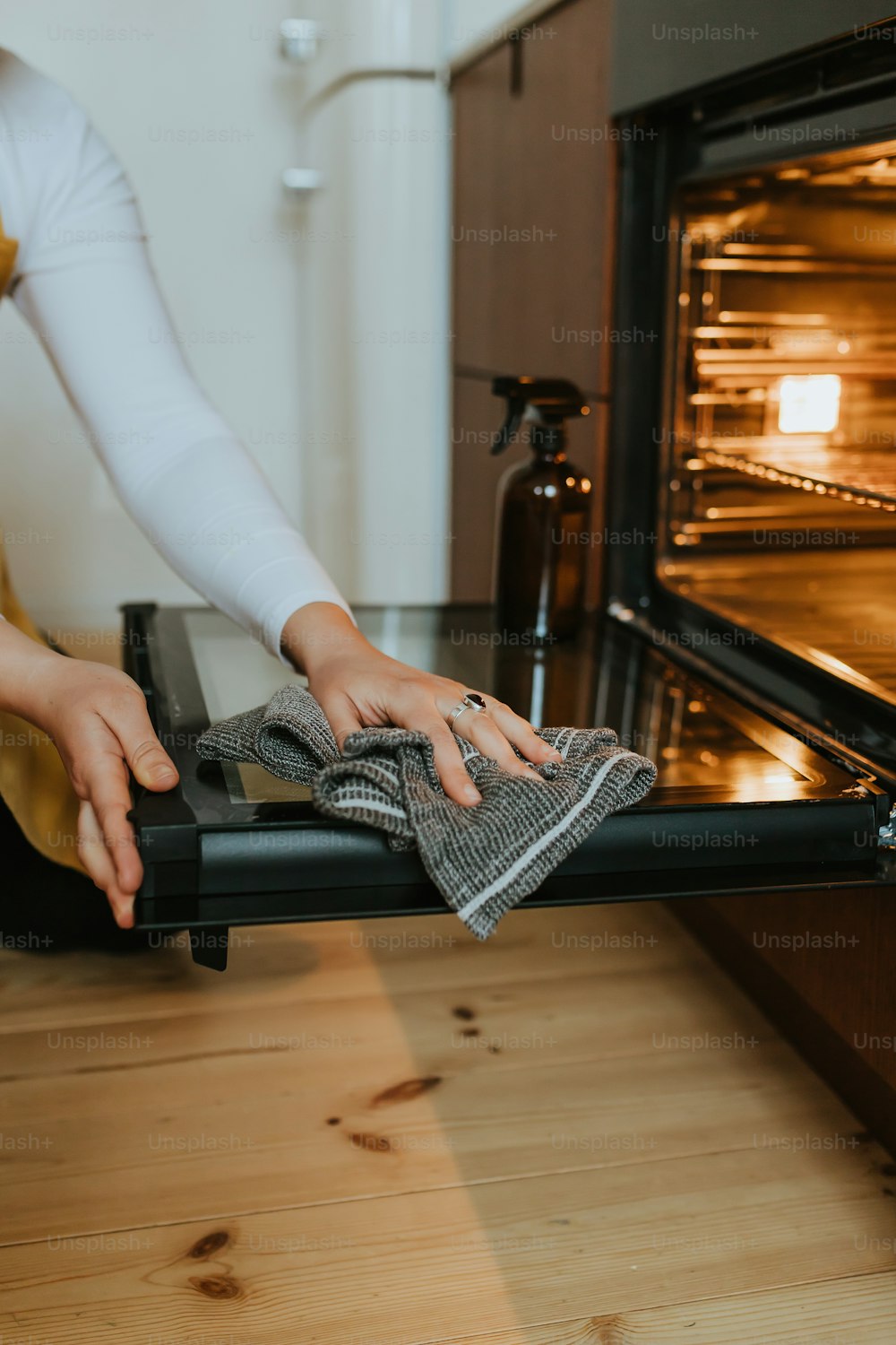 uma mulher está limpando o forno com um pano