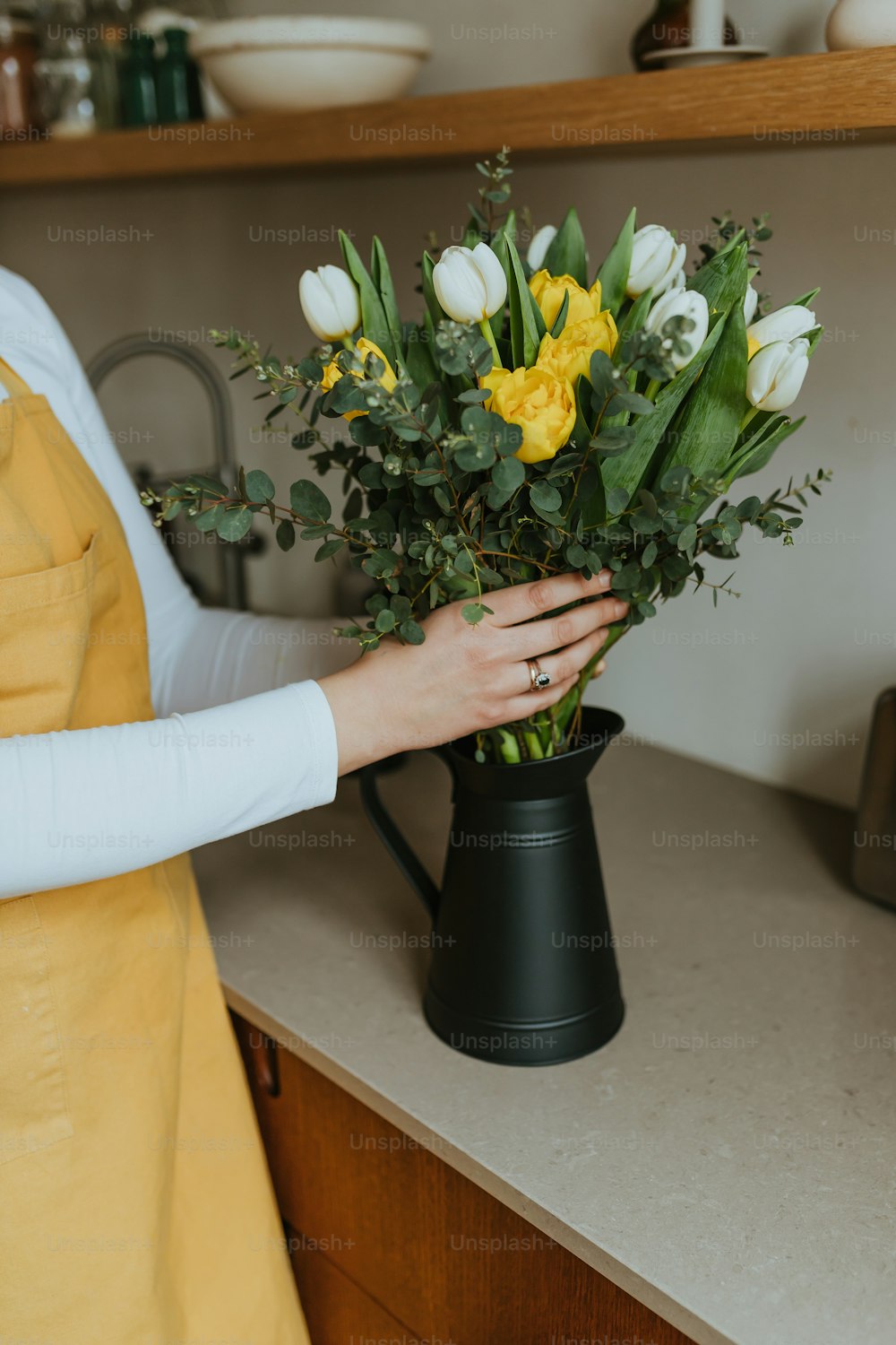 a woman holding a bouquet of flowers in a black vase