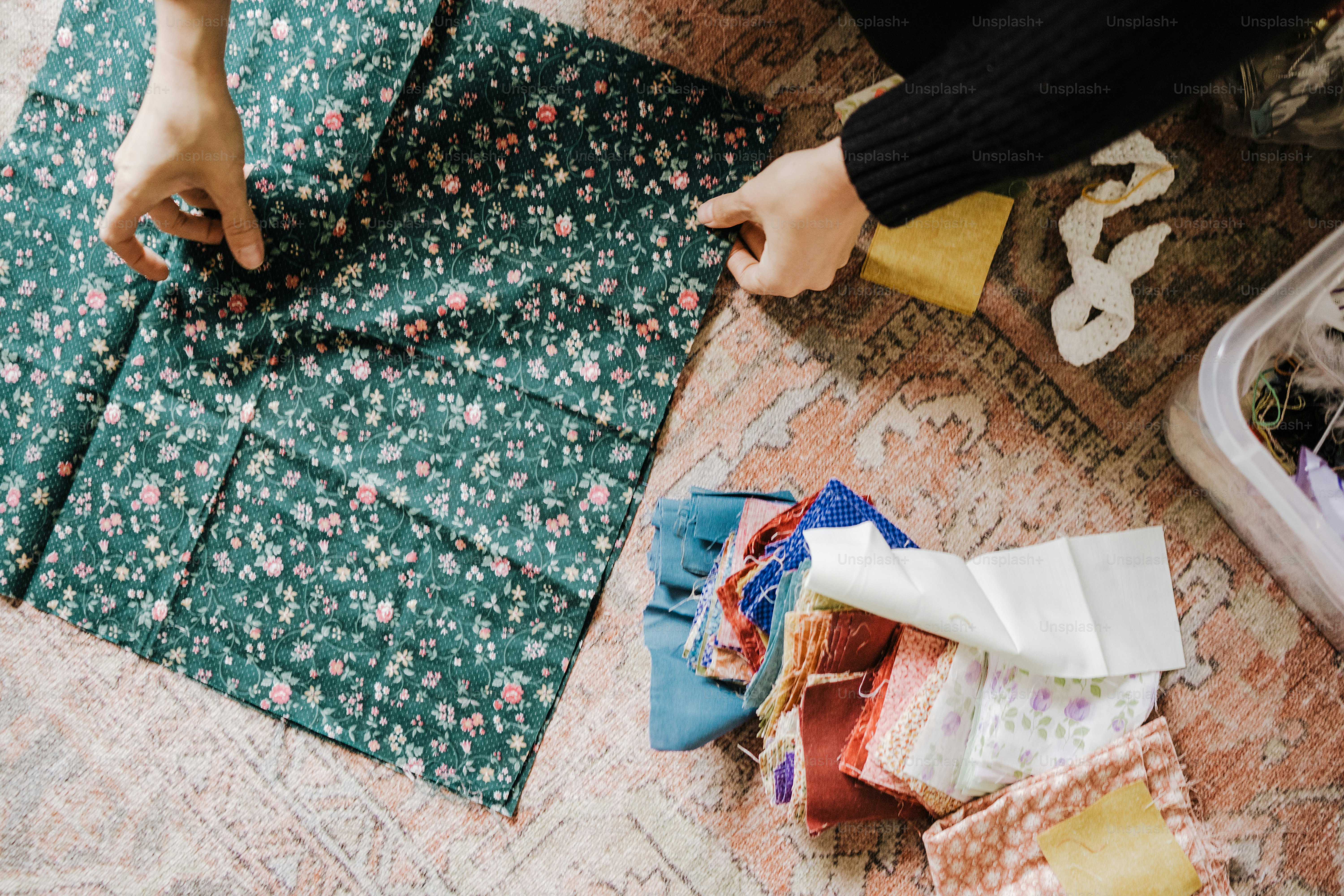 a person holding a piece of fabric next to a pile of fabric