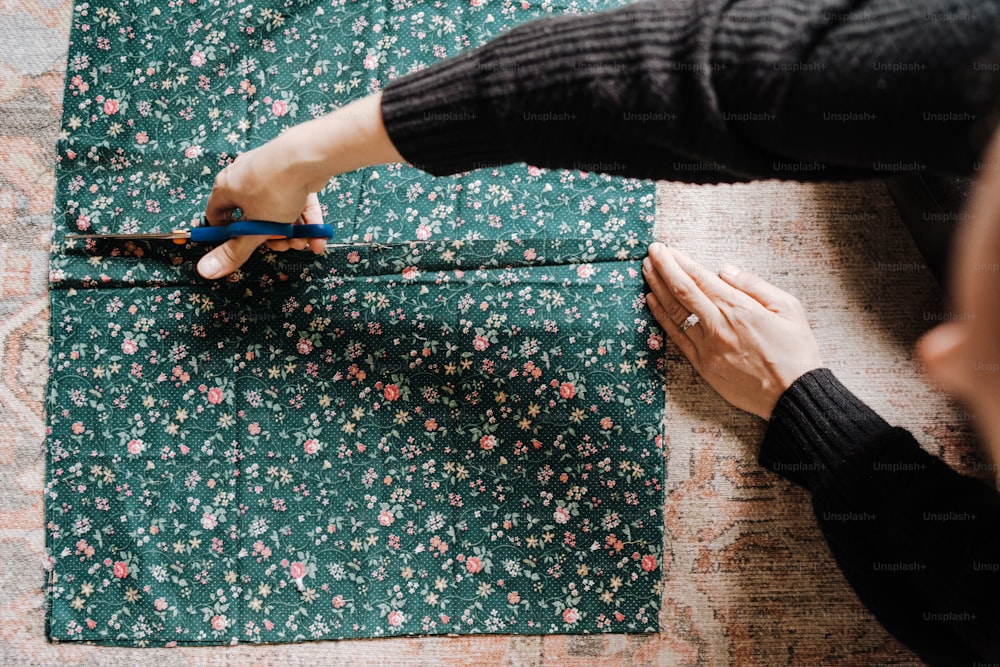 a person cutting fabric with scissors on a table