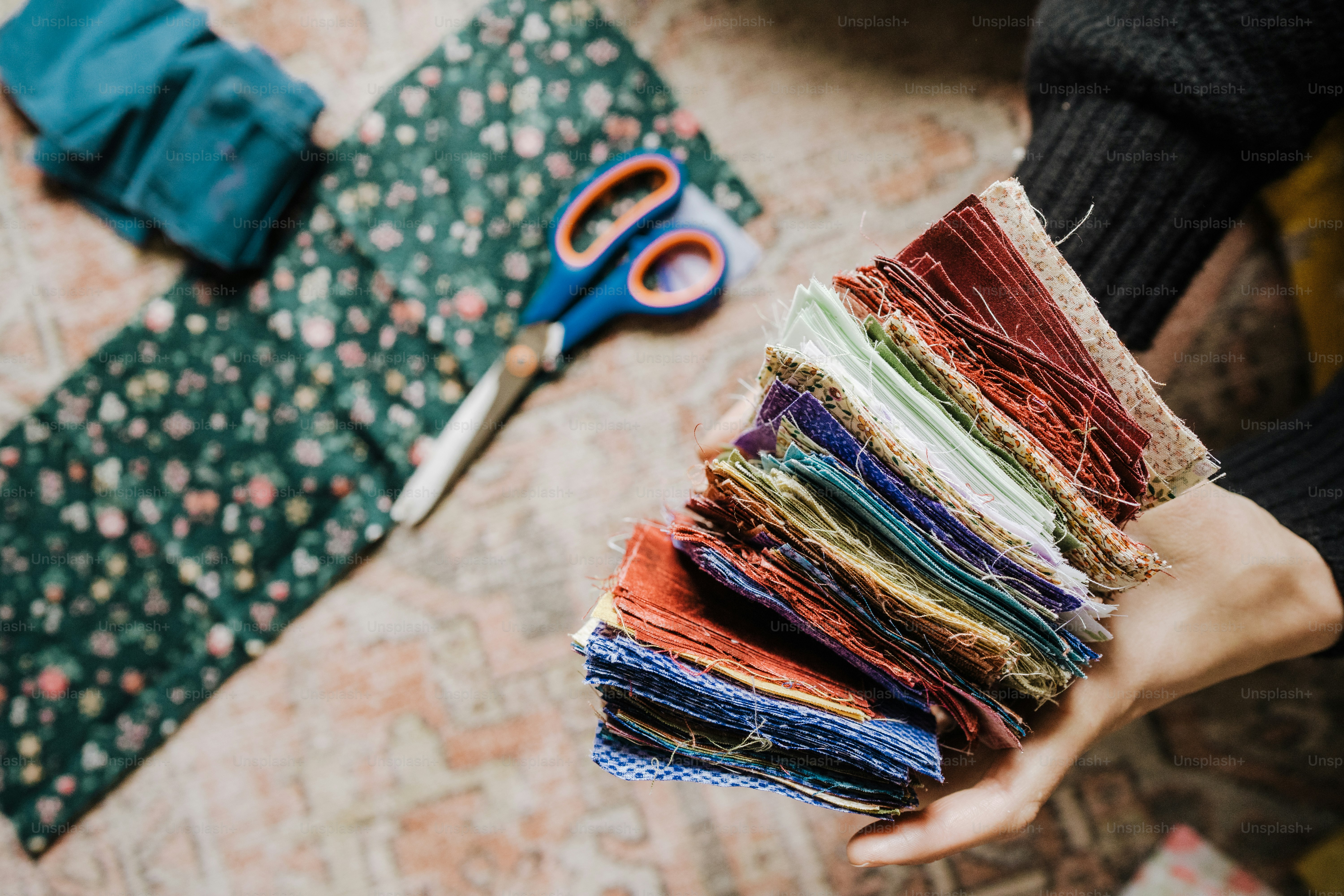 A person holding a stack of fabric next to a pair of scissors photo ...