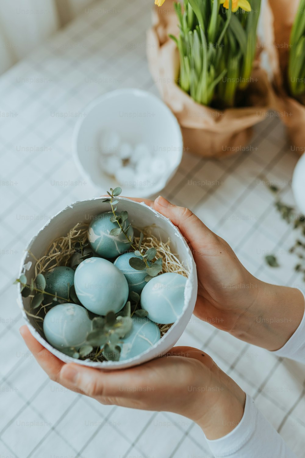 a person holding a bowl filled with blue eggs