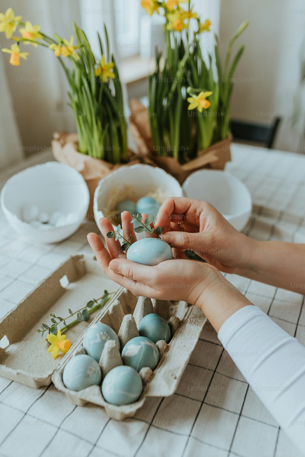 a person holding a bowl filled with blue and white eggs