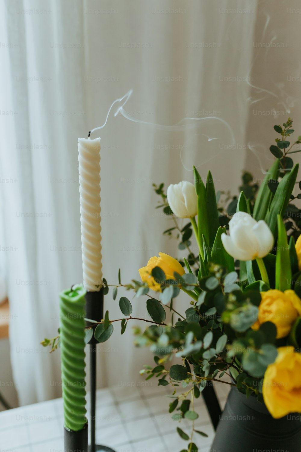 a vase with flowers and a candle on a table