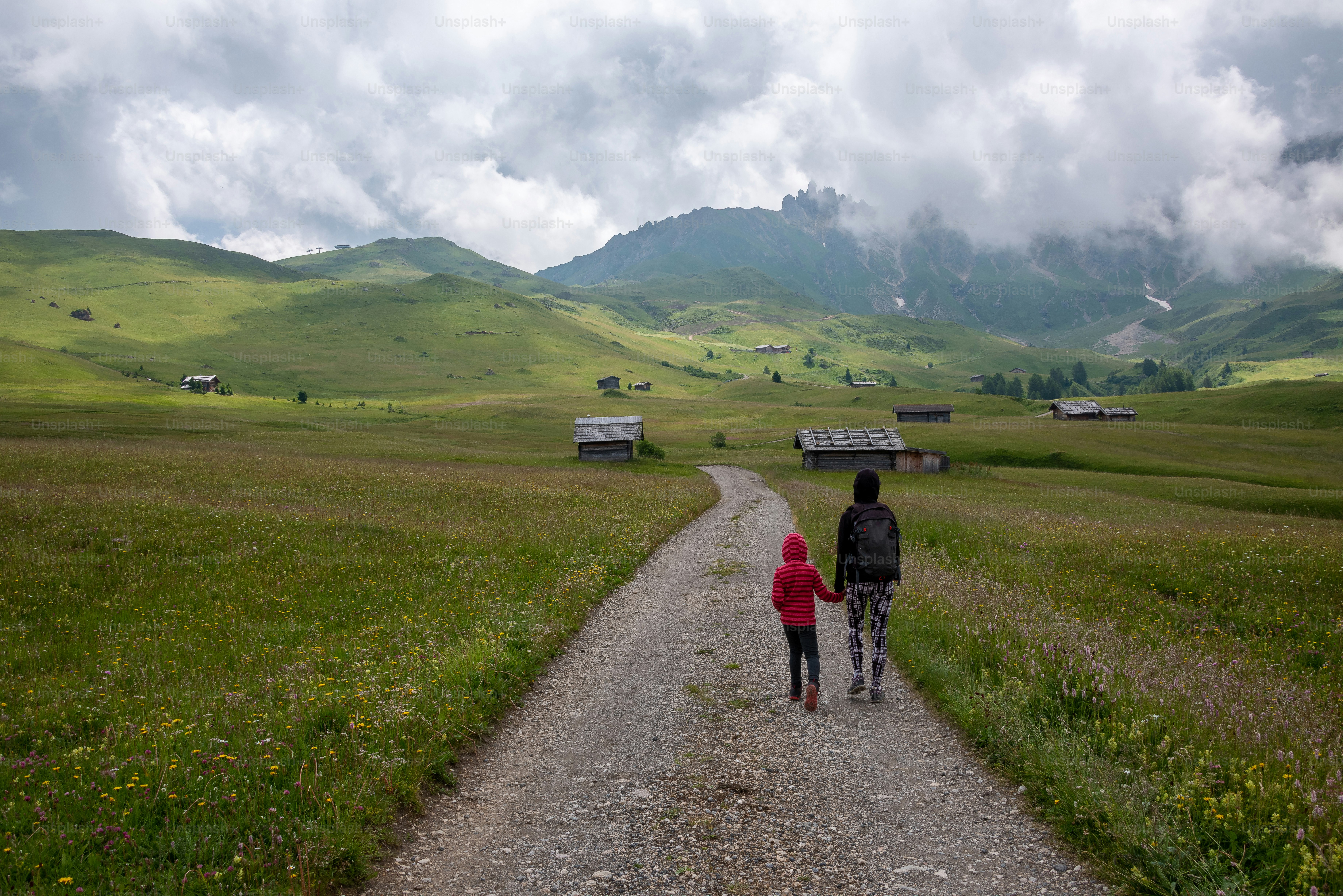 a couple of people walking down a dirt road