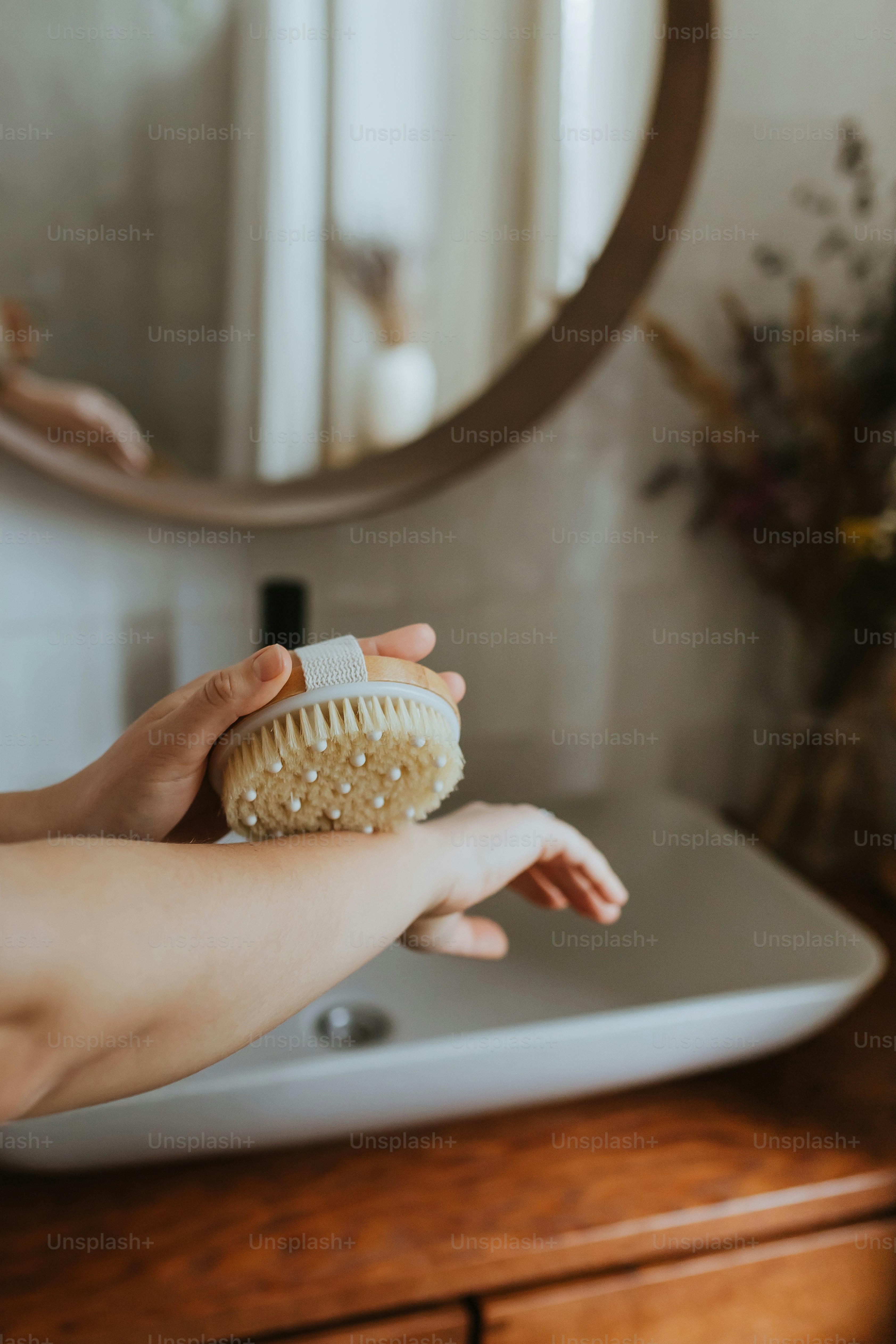 a woman is holding a brush in front of a mirror