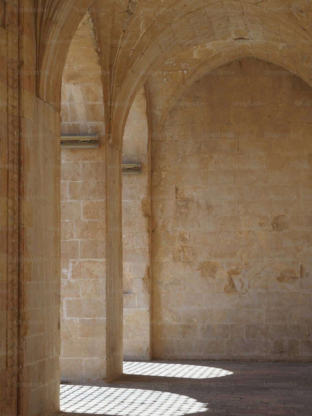 a stone building with arches and a bench in the middle