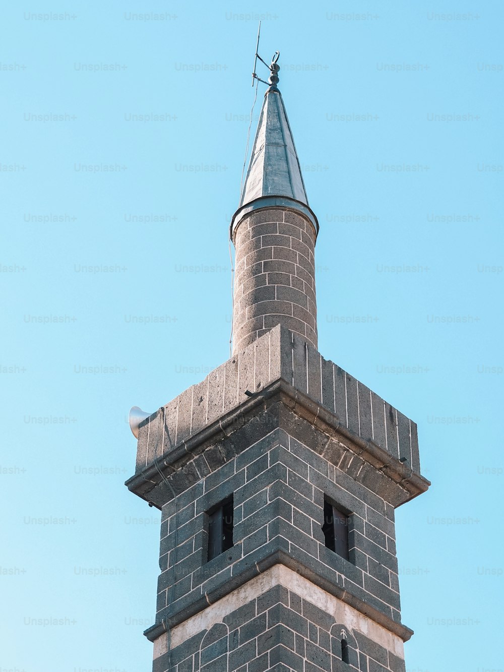 a tall brick tower with a weather vane on top